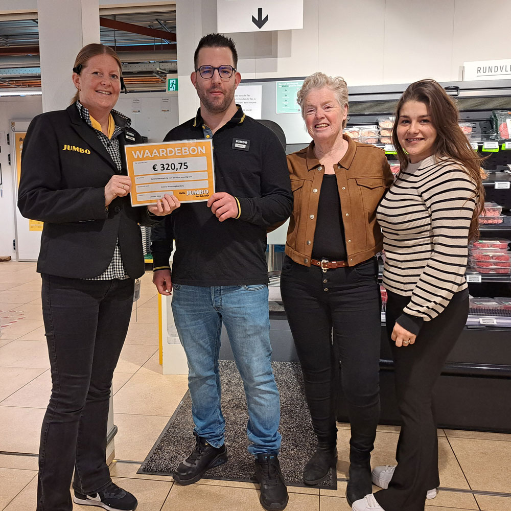 Drie mensen houden een bord vast voor een winkel, glimlachend en poseren voor de camera.